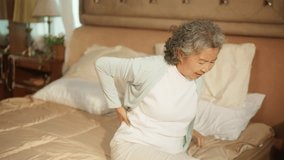 Asian senior mature woman suffering from backache. Elderly woman feeling pain on back and leg by the reason of degeneration of the discs and joints in spine, osteoarthritis or muscle inflammation. - Powered by Shutterstock - Get 15% off with code: PIKWIZARD15