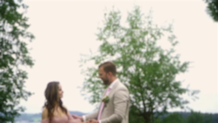 The groom kisses the bride in a beautiful romantic place. the bride and groom kiss against the background of beautiful nature. wedding event. blur