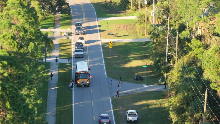 Yellow school bus picking up schoolkids on street bus stop for their lessons in Florida city suburbs. Public transport in the USA