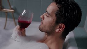 A close-up side view captures a man serenely enjoying red wine in a bathtub, embodying relaxation and indulgence - Powered by Shutterstock - Get 15% off with code: PIKWIZARD15