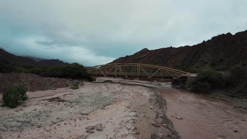 FPV drone flies between old bridge over the river. Morales Bridge. Quebrada las Conchas. Cafayate, Salta, Argentina.