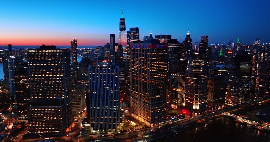 Beautiful buildings with light in windows in the scenery of Manhattan, New York, USA. A pink line is in the sky over the horizon at backdrop. Top view.