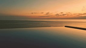 Orange Blue Infinity Pool Ocean Colorful Sky and Cirrus Clouds on the Horizon Slow Motion. Swimming Pool Sea and Beautiful Blue Orange Sky at Sunset. Vacation, Relax, Beauty, Luxury Resort, Travel. - Powered by Shutterstock - Get 15% off with code: PIKWIZARD15