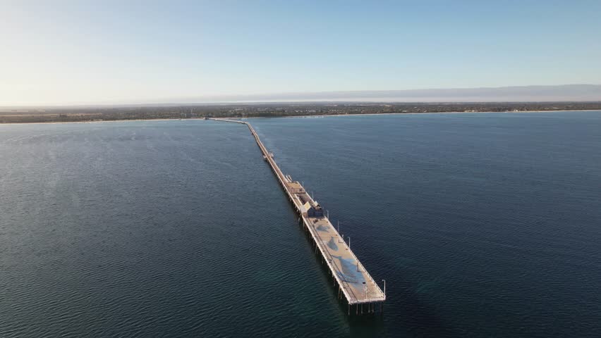 4K Drone video circling around Busselton Jetty surrounded by the vast blue ocean in Western Australia. The jetty is 1.841 kilometres long and is an iconic setting for beautiful nature surroundings.