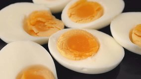 Hard-boiled eggs rotating on black background. Close up on many hard boiled eggs split in half, front view. - Powered by Shutterstock - Get 15% off with code: PIKWIZARD15