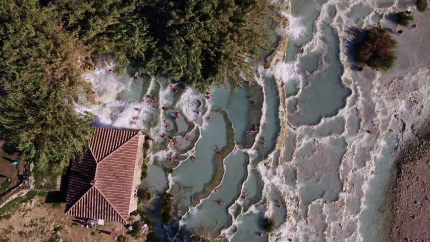 Aerial view of natural thermal spring pool with people bathing in river, Terme di Saturnia, Tuscany, Italy.