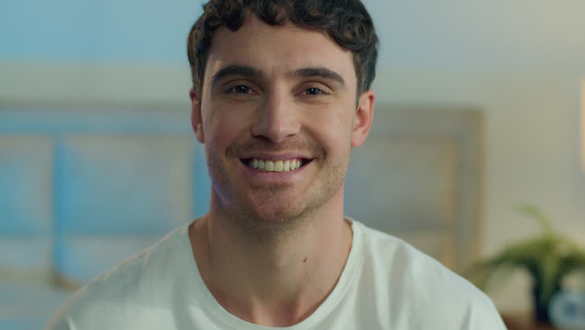 Close up confident Caucasian young happy man turn looking at camera smiling toothy dental smile guy home cheerful male inside joyful expression friendly carefree funny laughing enjoy bedroom laughter