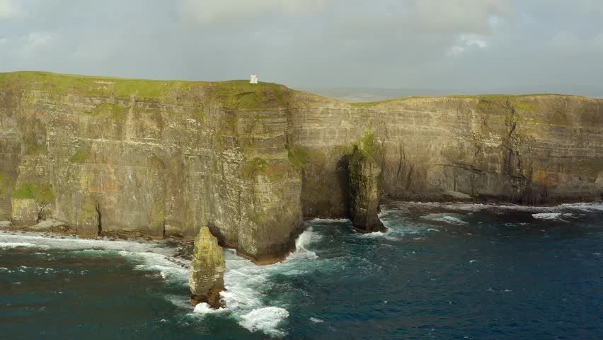 Aerial orbit of the Cliffs of Moher on a sunny, windy, and wavy day