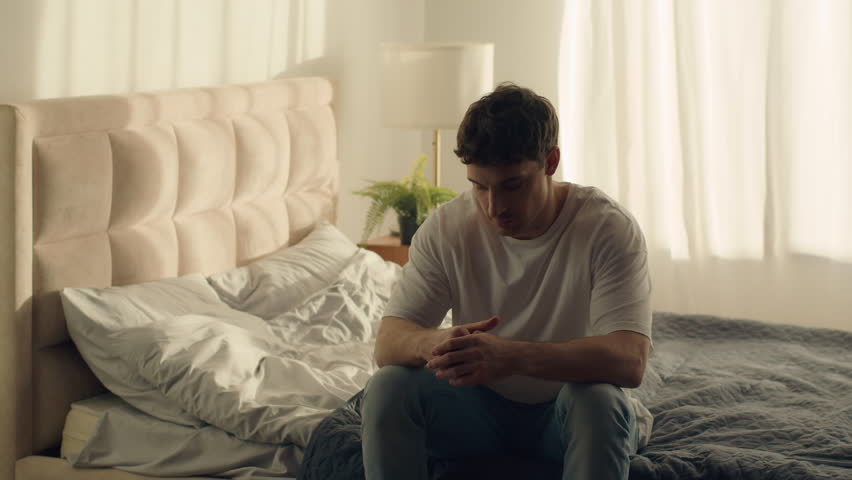 Caucasian man sitting on bed holding head grief pain crisis separation fatigue headache burnout bedroom guy male emotional stress tired exhaustion sadness anxiety distraught problems overworked loss