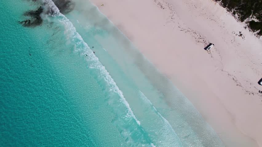 A 4K arial drone view looking down on Lucky Bay Beach in the Cape Le Grand National Park near Perth in Western Australia. You can see camper vans and 4-wheel drive vehicles parked on the beach.