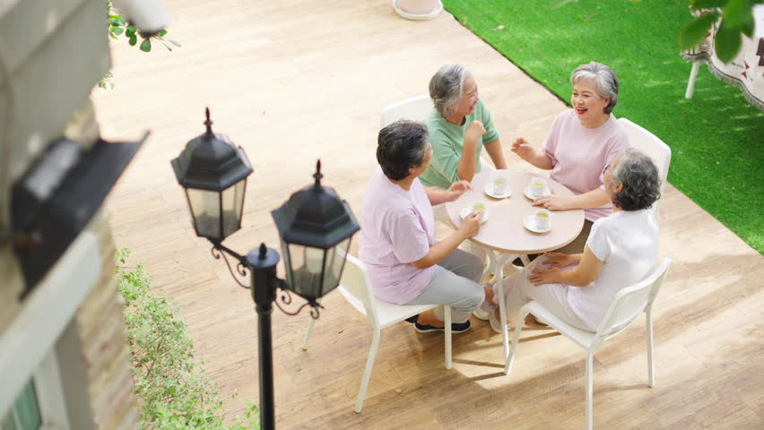 Group of Happy Asian senior mature women relax and enjoy indoor lifestyle meeting party together at home. Elderly retired woman friends drinking tea with talking together in the garden in summer day.