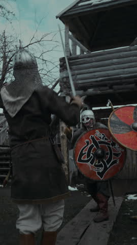 Full slowmo shot of skilled swordsman wielding two swords having furious combat with two enemy soldiers outdoors, while defending burning fortress in thick clouds of smoke
