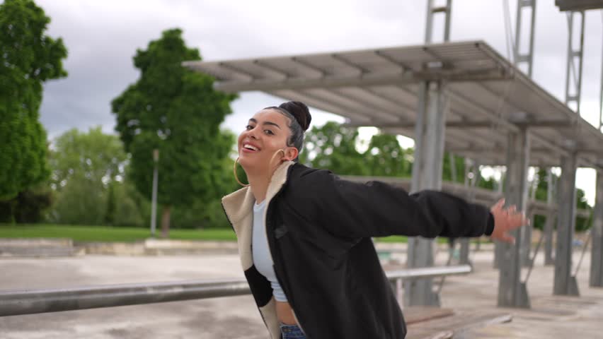A woman is posing for a picture in front of a building. She is wearing a blue tank top and blue jeans
