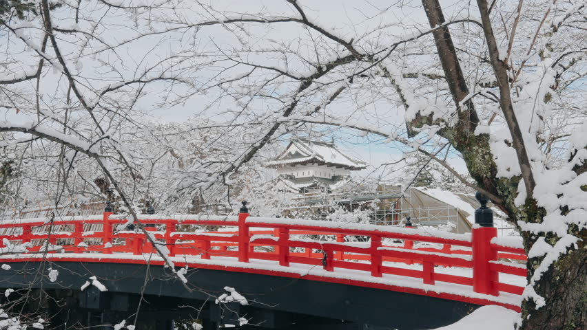 White Hirosaki Castle or Takaoka Castle and red bridge with snow in winter, hirayama style Japanese castle located in Hirosaki city, Aomori Prefecture, Tohoku, Japan. Landmark for tourist attraction