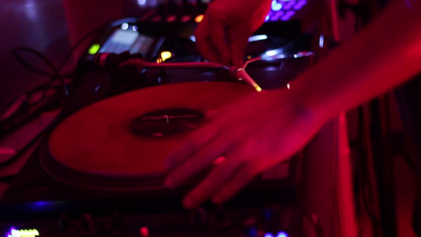 Spinning turntable dj hands in nightclub