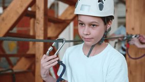 Portrait of a cute 12-year-old boy who walks an obstacle course in a rope park in protective gear with a calm face. Athletic children develop their body and spirit. A calm and focused boy climber. 4k - Powered by Shutterstock - Get 15% off with code: PIKWIZARD15