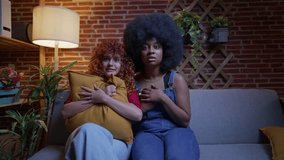 Two young women in their 20s express shock and fear while watching a scary movie on the couch. Two Friends Reacting to a Scary Movie at Home - Powered by Shutterstock - Get 15% off with code: PIKWIZARD15