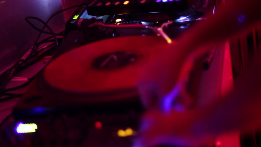 DJ scratching vinyl record plate in nightclub