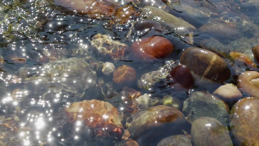 Sunlit pebbles in a stream, slow motion.
Close-up of stones in a shallow stream. Shot in the River Rea Canon Hill Park, Birmingham at 200fps.