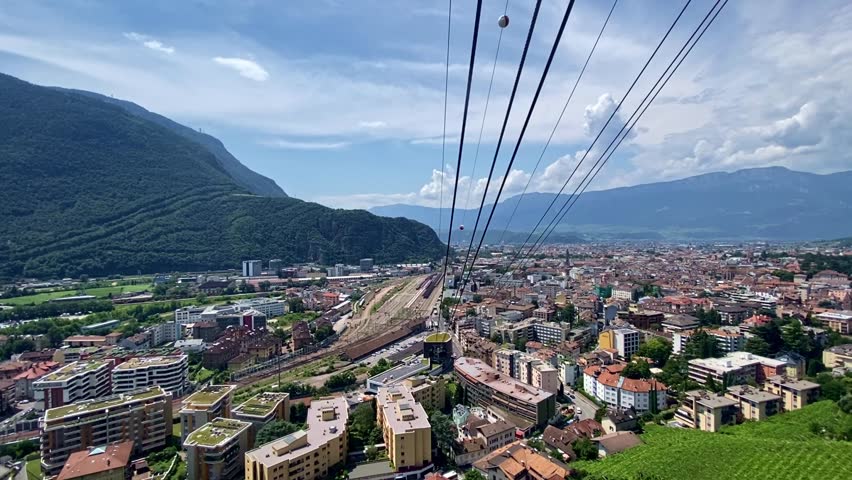 Aerial view from cable car way up of Italian City of Bolzano with scenic landscape on a sunny summer day. Movie shot July 17th, 2024, Bozen Bolzano, Italy.