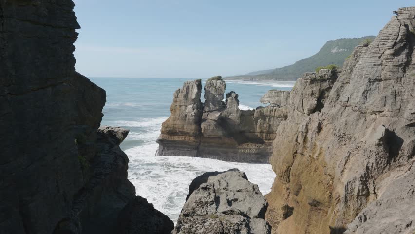 Waves crashing against rocks on a sunny summer day at Punakaiki Pancake Rocks, West Coast, New Zealand.