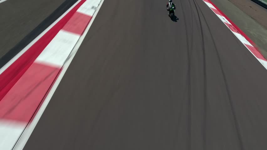 motorcyclist rides on a race track. Motorcycle racer training FPV drone
