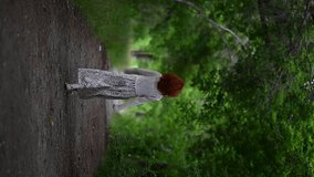 Vertical video of a young Asian woman in a white light dress, smiling, running along an alley of green trees - Powered by Shutterstock - Get 15% off with code: PIKWIZARD15