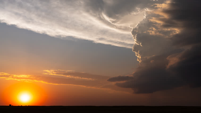 Moments before the sun sets, a beautiful storm drifts across the horizon, filling the sky with vibrant colors and dramatic clouds.