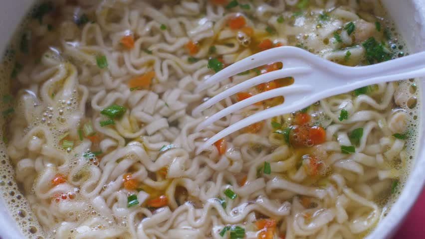 close-up of cooking instant noodle soup, instant noodles with plastic fork rotation