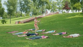 Yoga instructor guiding participants through final relaxation using wind chimes during outdoor session. Participants lying on mats in park for deep relaxation. Concept of mindfulness and meditation - Powered by Shutterstock - Get 15% off with code: PIKWIZARD15