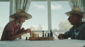 Grandfather plays chess with his grandson on the veranda of the house - Powered by Shutterstock - Get 15% off with code: PIKWIZARD15