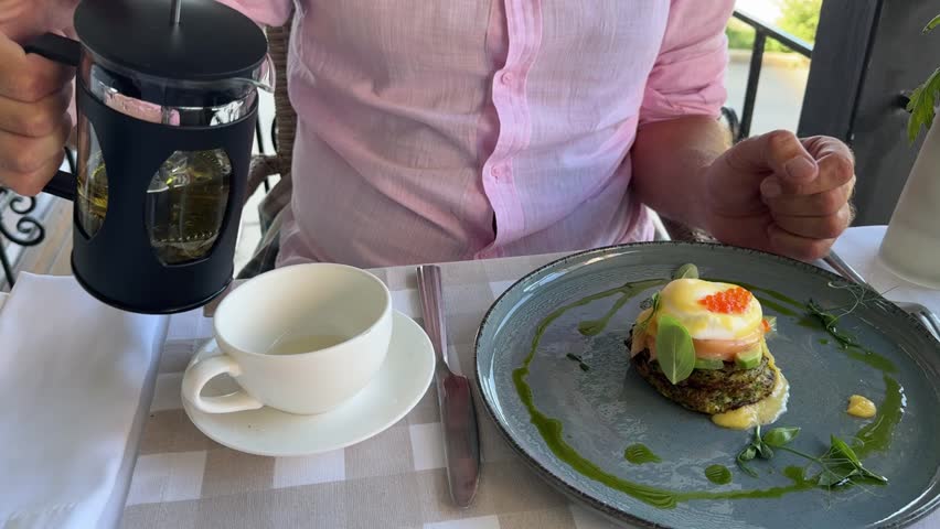 The man is about to take a bite of food, the man has lunch. A man in a pink shirt is having lunch.