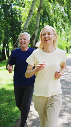 Elderly couple jogging together on a sunny day in park. Concept of senior fitness, healthy lifestyle and outdoor exercise