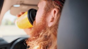 Rear view of a red bearded curly haired guy drinking takeaway coffee while driving a car during a break, sunny weather, close-up. - Powered by Shutterstock - Get 15% off with code: PIKWIZARD15