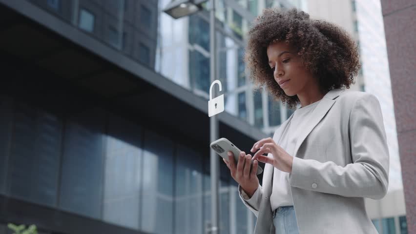 Businesswoman using a smartphone with a security hologram overlay, standing outside near business center. Concepts of financial data privacy and VPN service protection - Powered by Shutterstock - Get 15% off with code: PIKWIZARD15