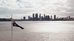 A view of the Perth city skyline from across the Swan River, with the Australian flag waving in the wind in the foreground. - Powered by Shutterstock - Get 15% off with code: PIKWIZARD15