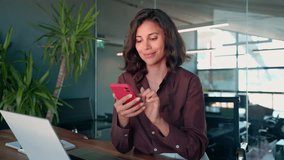 Young Indian business woman manager ceo using cell phone mobile app laptop. Smiling Latin Hispanic mature female businesswoman holding smartphone in office trading, reading, working online. Copy space - Powered by Shutterstock - Get 15% off with code: PIKWIZARD15
