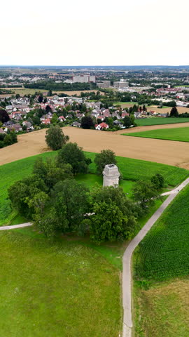 Aerial view of large field of green grass with a small building in the middle. Vertical video.