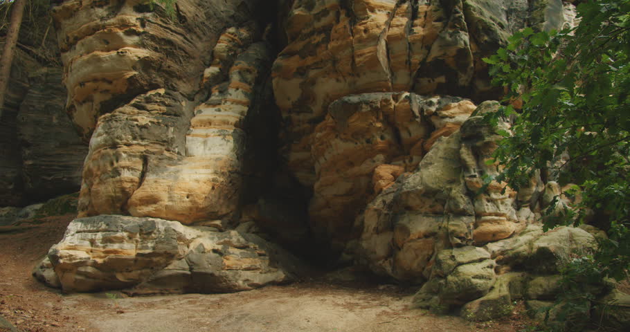 Towering rocky formations covered in moss and greenery in the forest, with layers of textured sandstone and green foliage framing the view. Bastei, Saxon Switzerland, Germany.