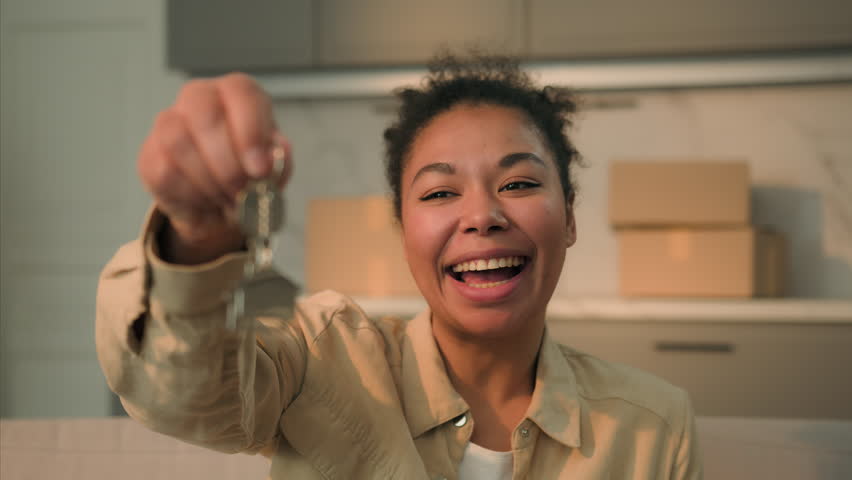 Happy African American woman joyful girl female buyer tenant laugh holding keys of new home buying own house buy rent apartment smiling homeowner real estate insurance loan mortgage credit moving day