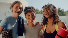 Three females in activewear looking at camera while laughing and holding equipment for multifunctional training. Best employees of gymnasium welcoming clients on terrace of white building. - Powered by Shutterstock - Get 15% off with code: PIKWIZARD15