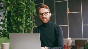 A young red-haired guy, a programmer or an entrepreneur in glasses, in a stylish cafe Looks at the camera and smiles. Freelancer works remotely. Online communication. small business. - Powered by Shutterstock - Get 15% off with code: PIKWIZARD15