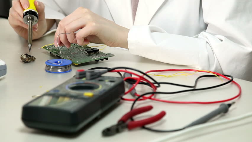 Girl solder wires to the circuit board in the electronics lab