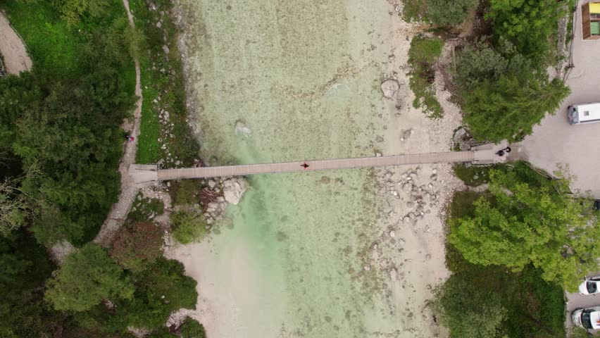 Aerial view of serene river valley with wooden bridge in Julian Alps, Bovec, Slovenia.