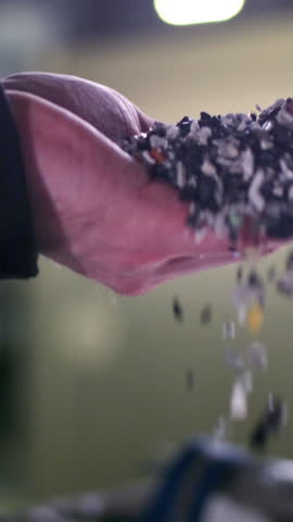 Worker pours pieces of recycled garbage from hand showing mission to promote environmental responsibility. Recycling process aims at minimizing waste and maximizing resource utilization