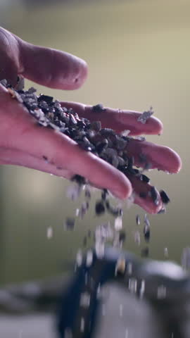 Worker pours pieces of recycled garbage from hand showing mission to promote environmental responsibility. Recycling process aims at minimizing waste and maximizing resource utilization