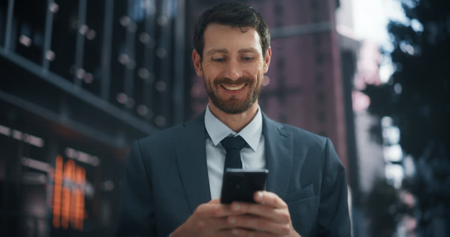 Caucasian Businessman in a Suit Navigates a City Street, Using With His Smartphone for Work, Social Media, and Online Shopping, Showcasing Urban Digital Connectivity and Productivity.