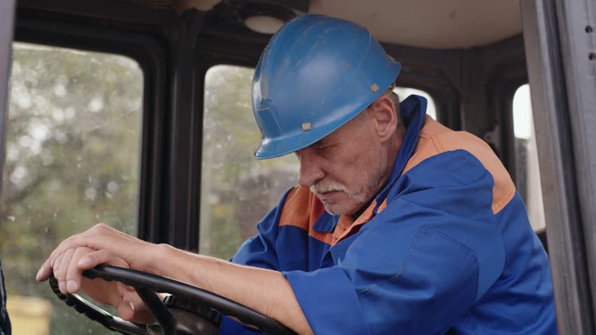 An exhausted construction worker taking a break and resting inside a vehicle cabin during the day