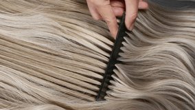 Closeup blond hair texture, slow motion of female hand combing long curly hair - Powered by Shutterstock - Get 15% off with code: PIKWIZARD15