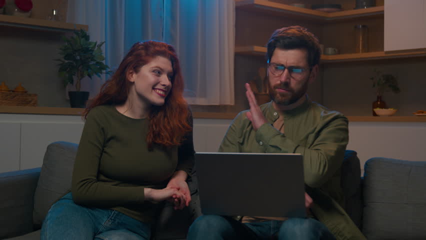 Focused busy Caucasian man businessman freelancer typing on laptop on couch home ignoring obsessive talking woman displeased husband annoyed with wife distracting from remote work relationship problem